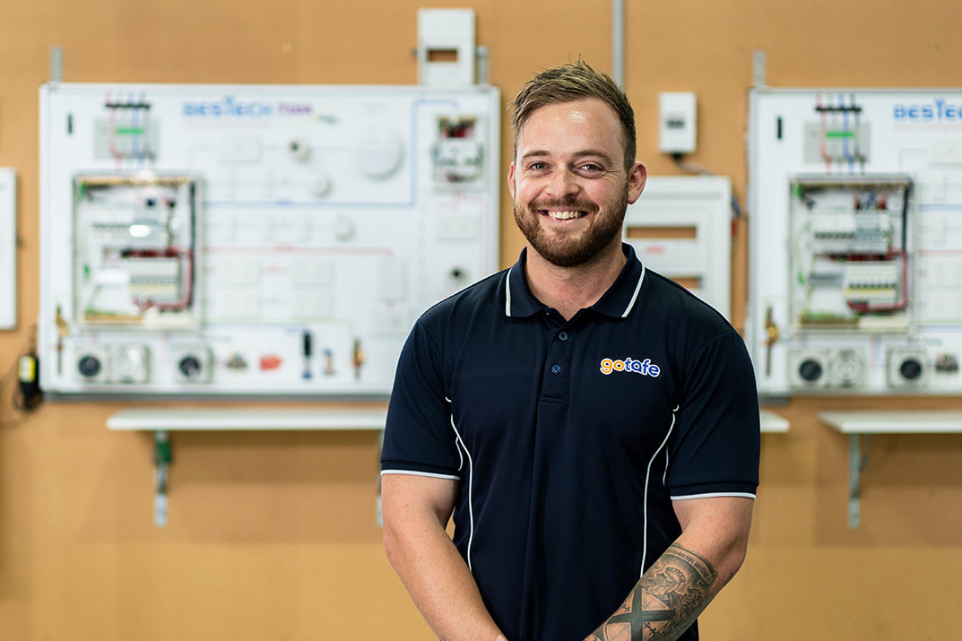 Electrotechnology teacher posing in front of an electrical board