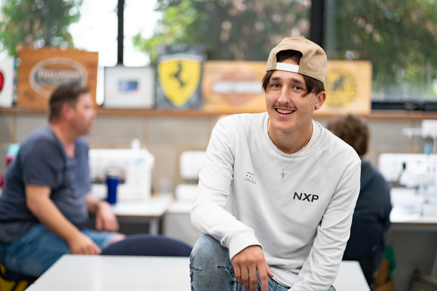 Young male student happily sitting in a common area on campus.